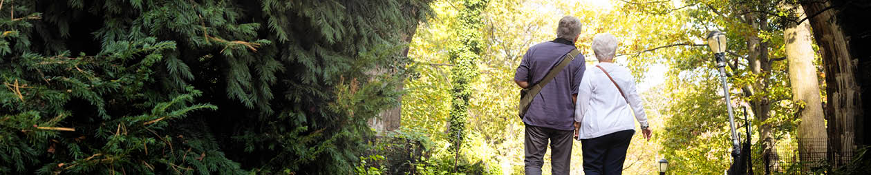 Senior couple discovering New-York City Fort Tryon park in Autumn  On this photograph, they walk under an arch hand in hand 