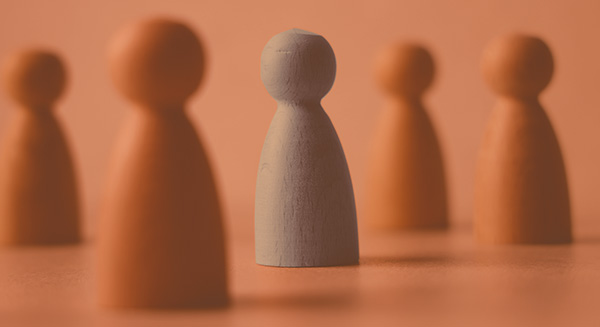 Selective focused group of wooden figures representing people, focusing on the center figure 