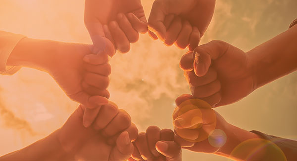 group of fists completing a circle with the sky in the background