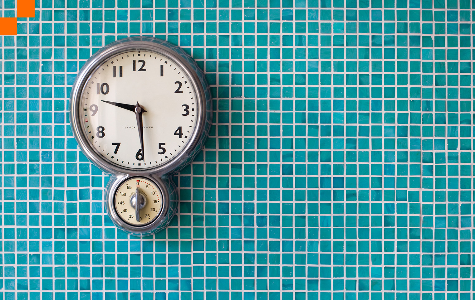 Retro chrome clock on a teal tile wall